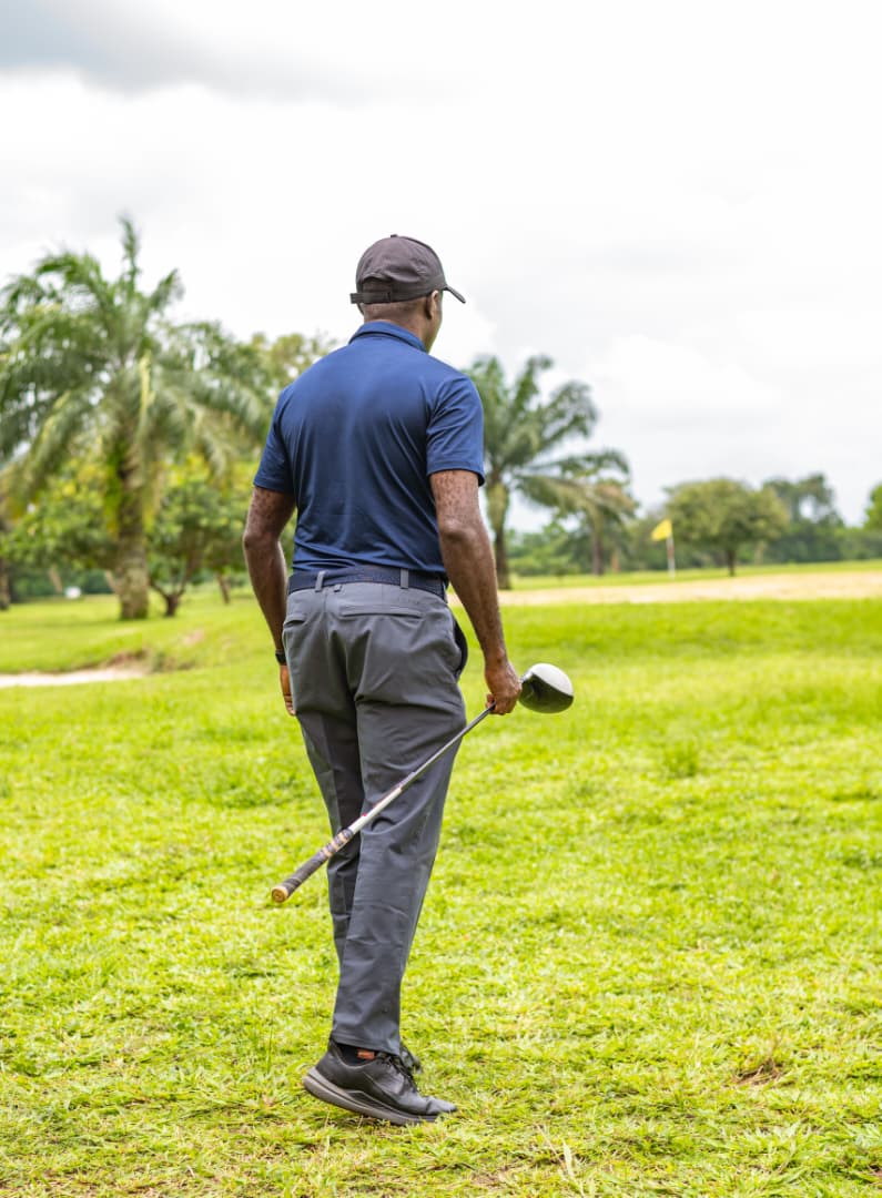 Player walking towards the green under the palms