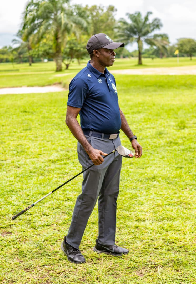 Member in navy polo surveying the fairway, palms behind